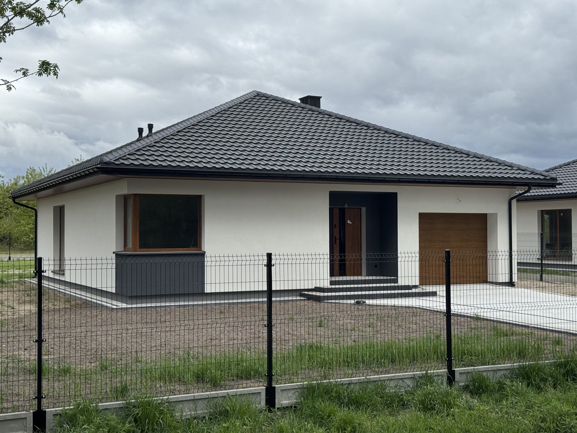 Front domu parterowego z garażem i wybrukowanym podjazdem